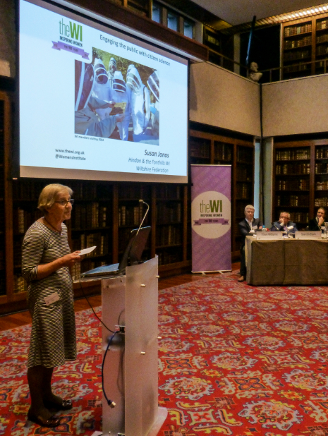 A woman standing in front of a large screen speaking to the audience at the Bee Summit