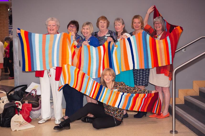 Women holding up a multicolored scarf