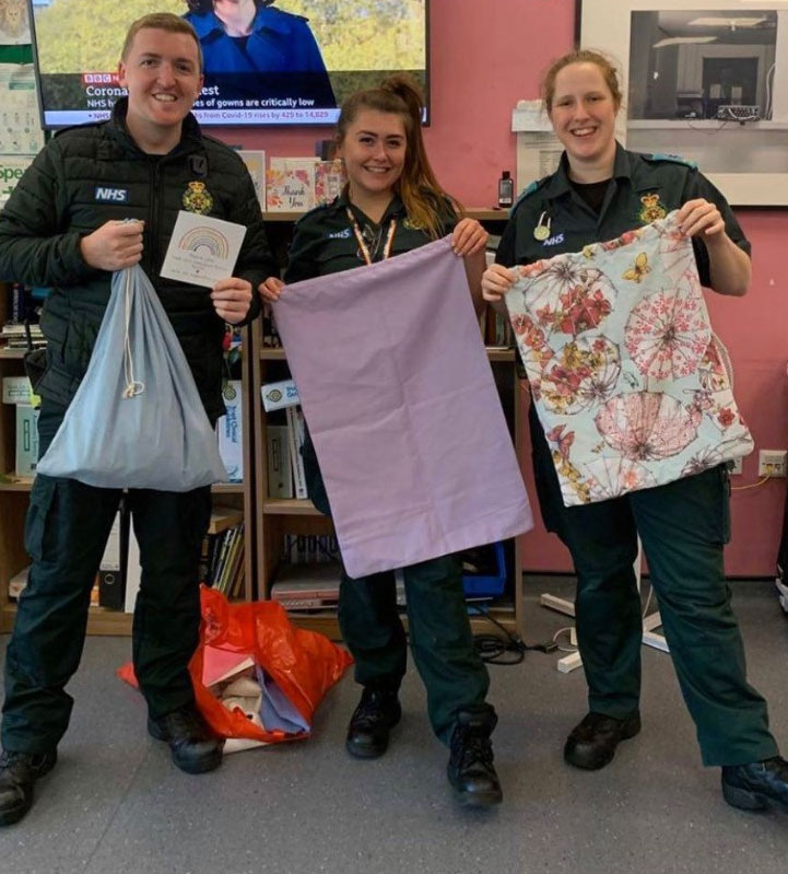 Three people holding up handmade laundry bags