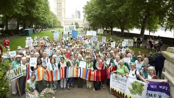 A large group of WI members holding up signs at the Time is Now Climate Change mass lobby 2019