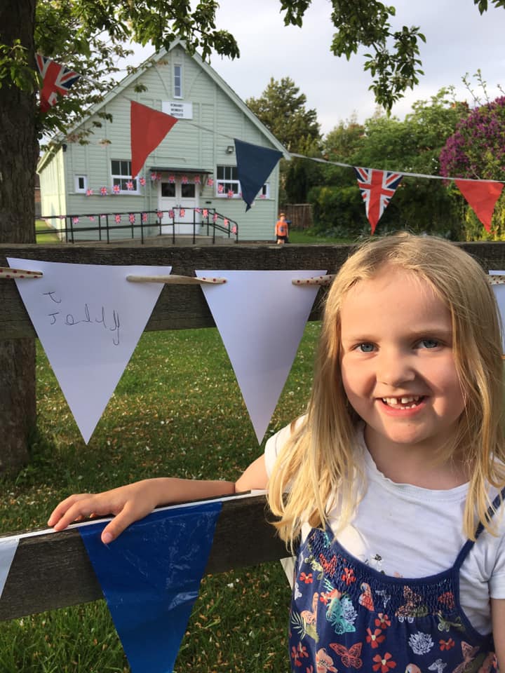 A girl standing next to bunting at a fence